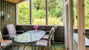 A covered patio with a glass table and chairs, a wooden ceiling, and a view of greenery outside. - 8 Person Holiday Home in Ans By (Ans)