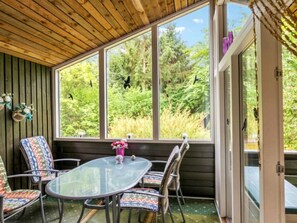 A covered patio with a glass table and chairs, a wooden ceiling, and a view of greenery outside. - 8 Person Holiday Home in Ans By (Ans)