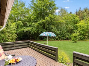 A wooden deck with a round table, a bench, and a floral umbrella. - 8 Person Holiday Home in Ans By (Ans)