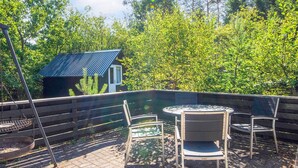 An outdoor patio with a table and chairs, a metal grill, and a small cabin in the background. - 8 Person Holiday Home in Ans By (Ans)