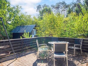An outdoor patio with a table and chairs, a metal grill, and a small cabin in the background. - 8 Person Holiday Home in Ans By (Ans)