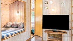 A room with a bed, a TV, and a wooden wall. - 8 Person Holiday Home in Ans By (Ans)