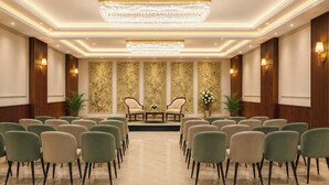 A conference room with a chandelier, two armchairs, and a row of chairs.