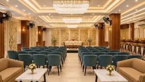 A hotel conference room with rows of chairs, a sofa, and a chandelier.