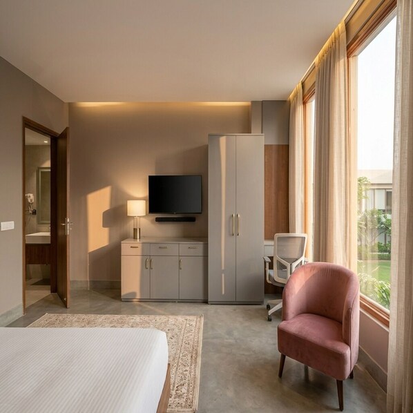 A hotel room with a bed, a television, a desk, a chair, and a wardrobe.