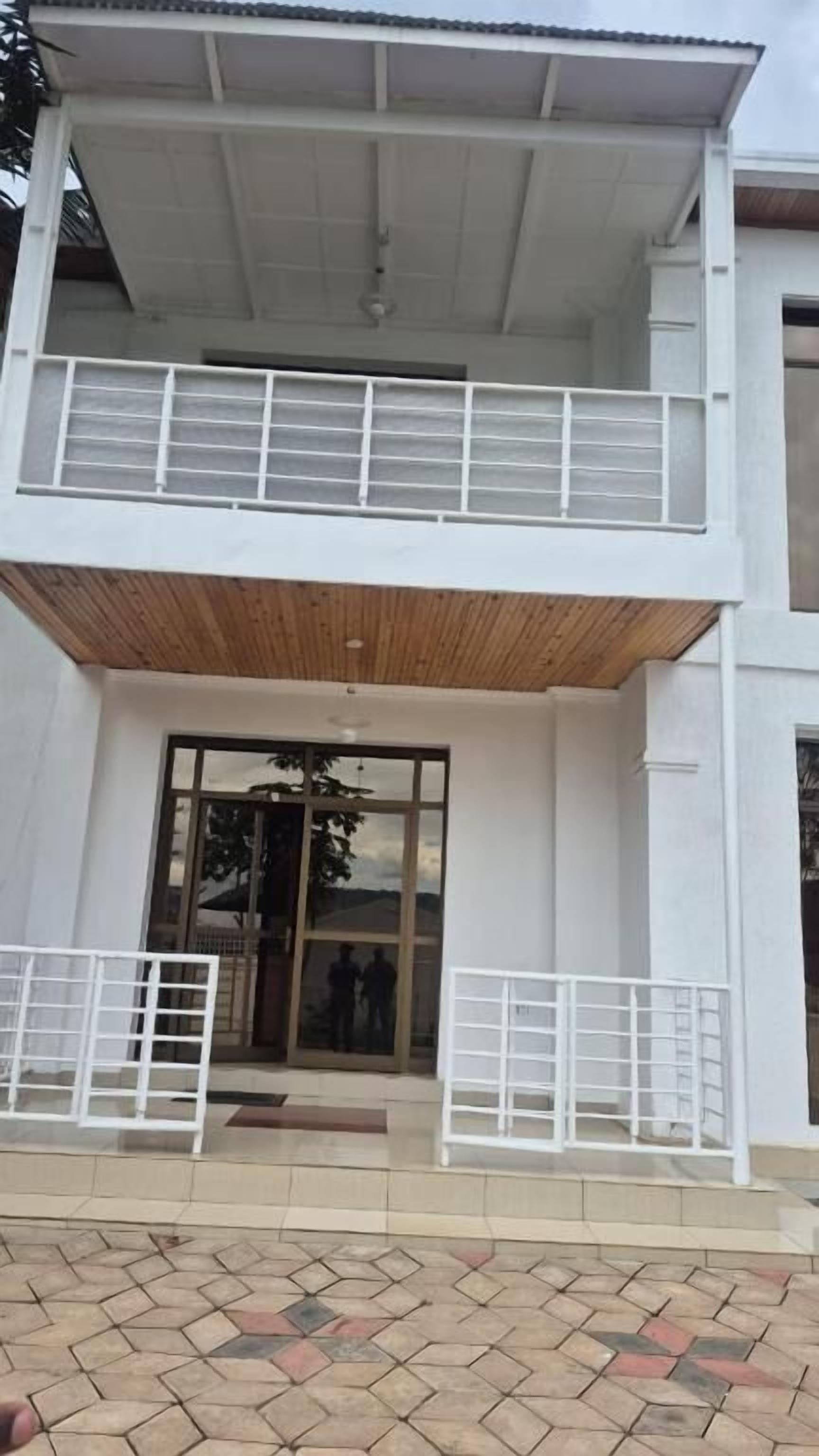 Un edificio de dos plantas con balcón, puertas de cristal grandes y una zona de entrada con tejas.