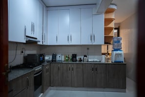 A kitchen with white cabinets, a microwave, a coffee maker, and a water dispenser. - KAZE CONSOLIDATE HOME INN (Kigali)
