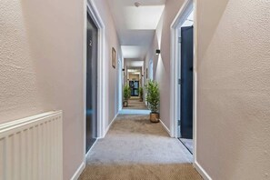 A hallway with a carpeted floor, white walls, and doors on both sides. - Triple Studio Flat (Sleeps 3) with Parking | CV2 (Coventry)