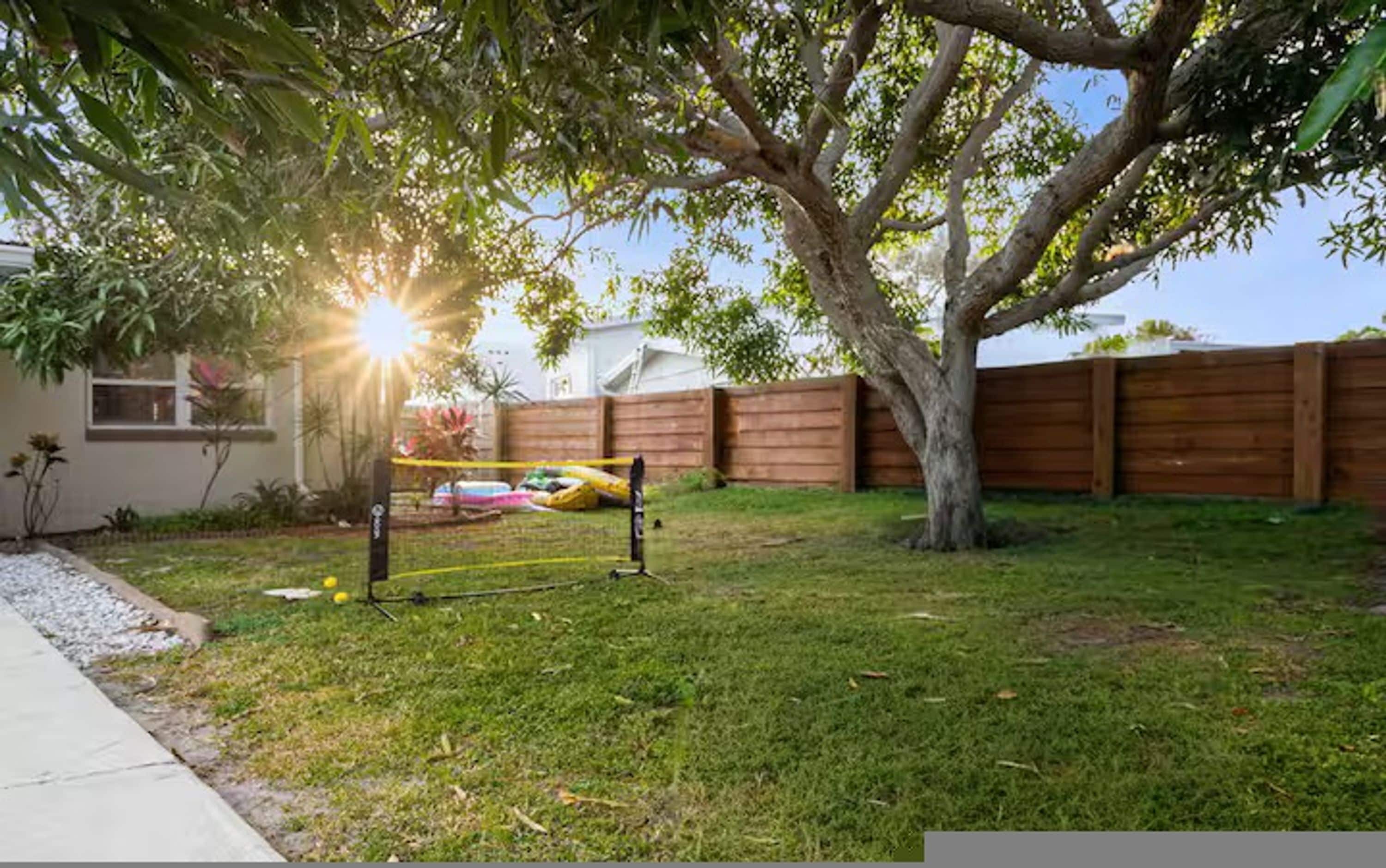 Ein Garten mit Baum, Holzzaun und Trampolin.