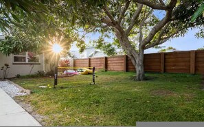 Ein Garten mit Baum, Holzzaun und Trampolin.