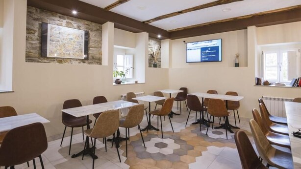 A conference room with tables and chairs, a projector screen, and a stone wall with a framed map.