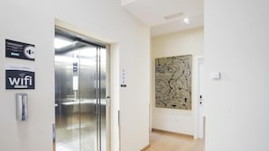A modern elevator, a wall-mounted artwork, and a sign indicating wifi availability.