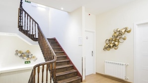 A staircase with wooden steps and a handrail, a white wall with a radiator, and a decorative wall piece.
