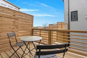 A wooden deck with a table and chairs, a wooden fence, and a building in the background. - 4BR Raleigh Townhome Near Downtown (Sleeps 9) (Raleigh)