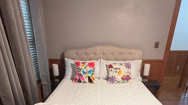 A bed with a tufted headboard, two decorative pillows, and a white bedspread. - 3-bedroom house in beautiful Spring with amazing Pool (Spring)