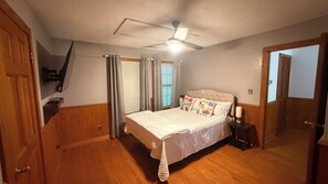 A bedroom with a bed, a nightstand, a ceiling fan, and a door. - 3-bedroom house in beautiful Spring with amazing Pool (Spring)