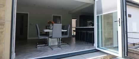 A modern house with a sliding glass door leading to an open-plan living area and dining space.