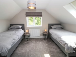 Ein Schlafzimmer mit zwei Betten, einem Fenster, einer Heizung und einer Deckenleuchte.