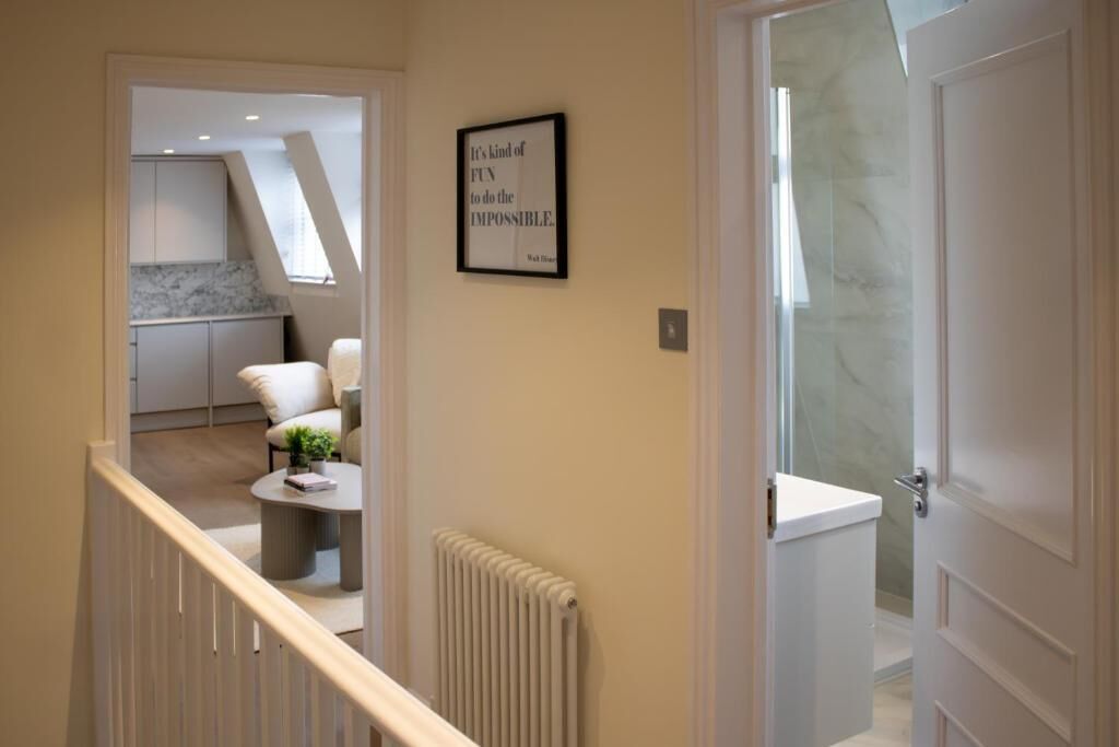 Un interior moderno con una escalera que lleva a una zona de cocina, una cita enmarcada en la pared y una puerta blanca.