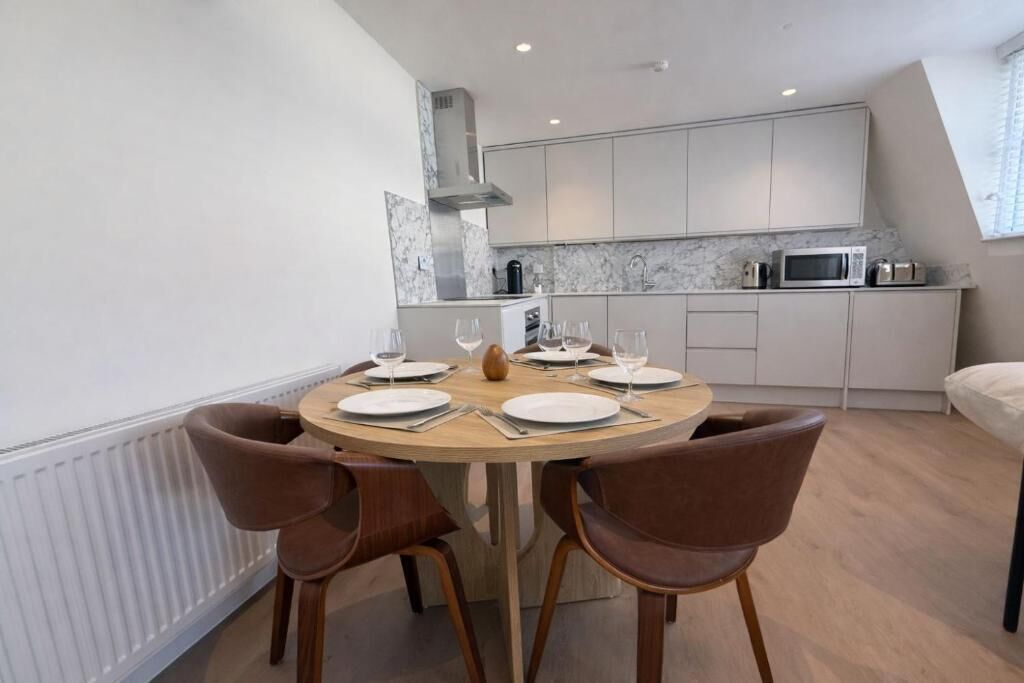 Un comedor con una mesa redonda, cuatro sillas y una cocina al fondo.