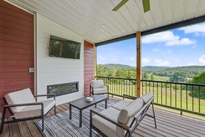 Un espacio de estar al aire libre techado con chimenea, una mesa y sillas, con vistas a un paisaje pintoresco.