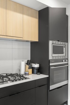 Une cuisine moderne équipée d’une cuisinière à gaz, d’un four à micro-ondes et d’un four encastré.