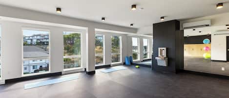 A spacious, modern room with large windows, a dark floor, and minimalistic decor.