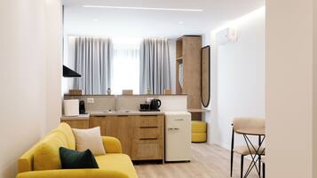 Una kitchenette moderna con refrigerador, cafetera y un pequeño comedor con una silla.