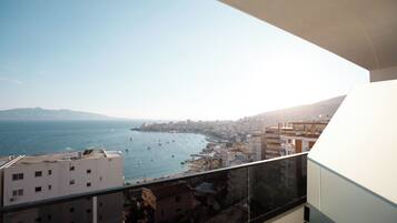 Un balcón con vistas a una ciudad costera, que incluye edificios y el mar.