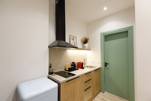 A compact kitchen with a built-in stove, a sink, and a small refrigerator. - Oleva Suites (Sarande)