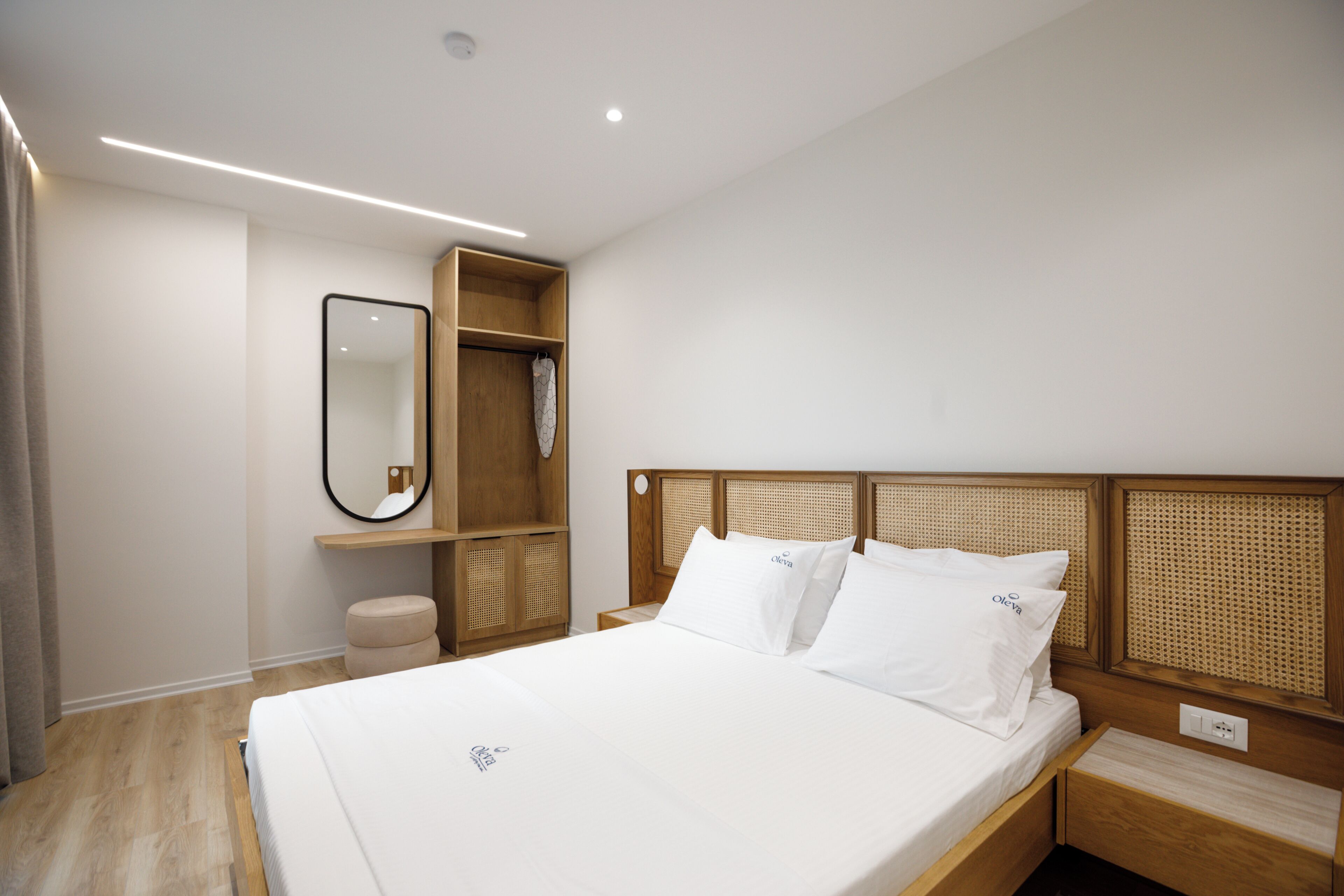 Una habitación de hotel con una cama, un cabecero de madera, un espejo y un pequeño armario de madera.