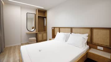 Una habitación de hotel con una cama, un cabecero de madera, un espejo y un pequeño armario de madera.