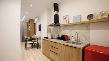 Cocina moderna con armarios de madera, pileta de acero inoxidable y refrigerador rojo.