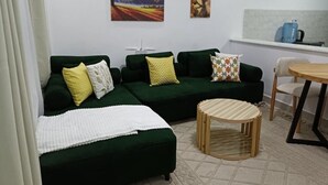A living room with a green sofa, a round wooden coffee table, and a kitchen area in the background. - J & M Homes 2 bedroom unit (Naivegas apartment) (Naivasha)