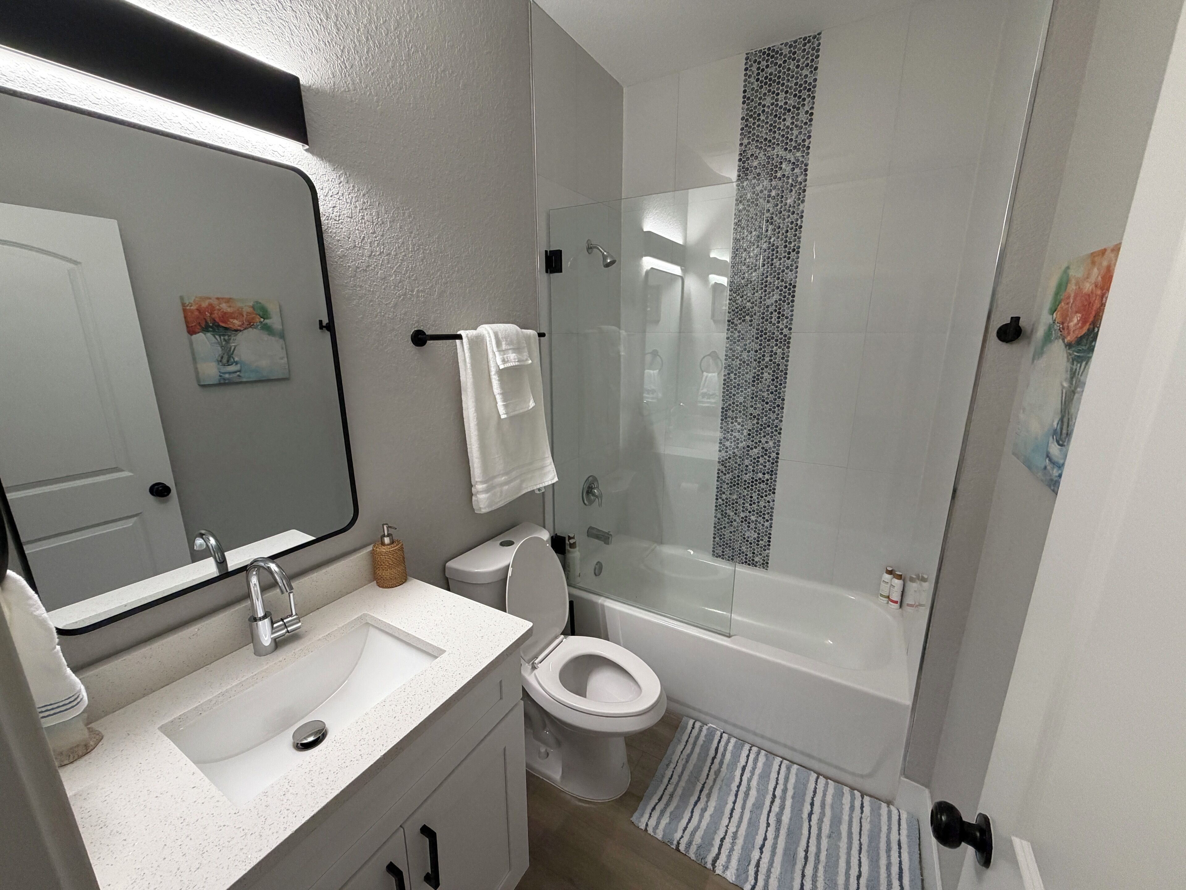 A modern bathroom with a white sink, toilet, and bathtub.