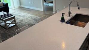 Una cocina moderna con una isla grande, un lavaplatos integrado y un televisor de pantalla plana montado en la pared.