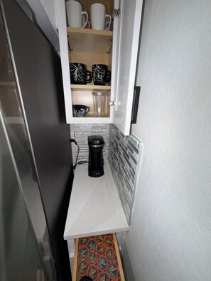 A kitchen with a coffee maker, a cabinet with mugs, and a tray of packaged food. - Gorgeous Coastal Townhome - 8 min from Boca Grande, Close to Beaches & Shops (Port Charlotte)