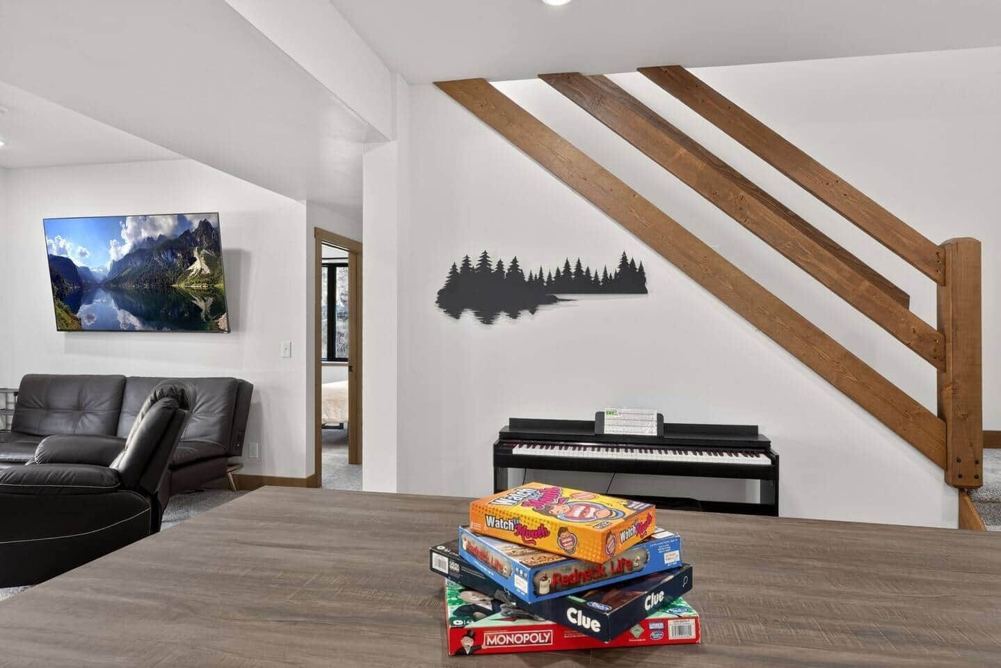 A living room with a piano, a couch, and a wall with a nature scene.