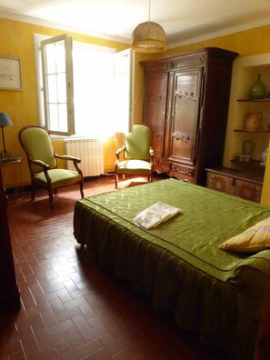 A room with a bed, two chairs, a cabinet, and a hanging light fixture. - Country House, Cévennes 30 (Gard) (Saint-Laurent-le -Minier)