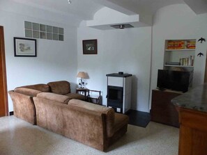 A living room with a sofa, a television, a fireplace, and a bookshelf. - Country House, Cévennes 30 (Gard) (Saint-Laurent-le -Minier)