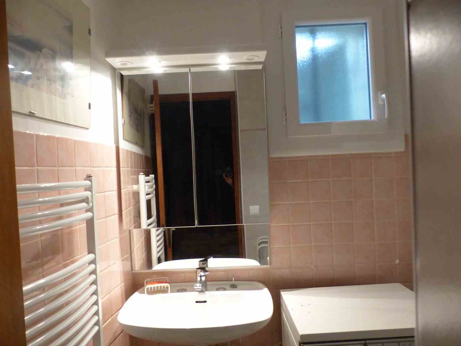 A bathroom with a white sink, a mirror, a window, and a towel rack.