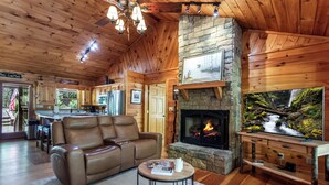 A cozy cabin interior with a leather sofa, a fireplace, a stone wall, and a wooden ceiling. - 5 min to Aska Adventure area! Hot Tub + Fireplace, Dog Friendly, Fire pit (Blue Ridge)