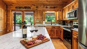 A kitchen with wooden cabinets, a marble countertop, a stainless steel refrigerator, and a wine bottle. - 5 min to Aska Adventure area! Hot Tub + Fireplace, Dog Friendly, Fire pit (Blue Ridge)
