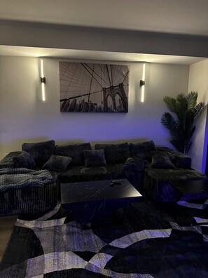 A modern living room with a sectional sofa, a coffee table, and a large cityscape painting on the wall. - Downtown Beauty (Atlanta)