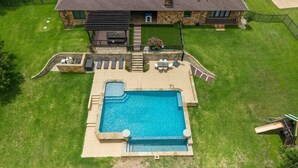 Ein Haus mit Swimmingpool, Terrasse und Sitzgelegenheiten, sowie einer Fassade aus Naturstein.