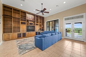 A living room with a sectional sofa, wooden shelving, a flat-screen TV, and a ceiling fan. - Wanderers Haven - pool + media room, gatherings (Belton)