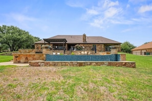 A house with a stone exterior, a covered patio, and a swimming pool. - Wanderers Haven - pool + media room, gatherings (Belton)