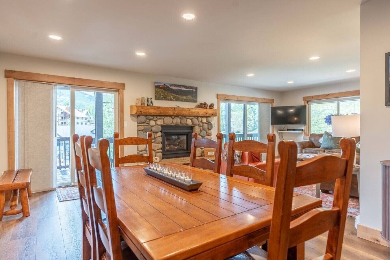 A dining room with a wooden table, chairs, a fireplace, and a television.