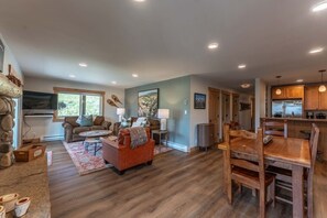 A spacious living area with a fireplace, a dining table, and a kitchen with wooden cabinets. - Evergreen Paradise - Hot Tub, Fireplace, Walk to (Crested Butte)