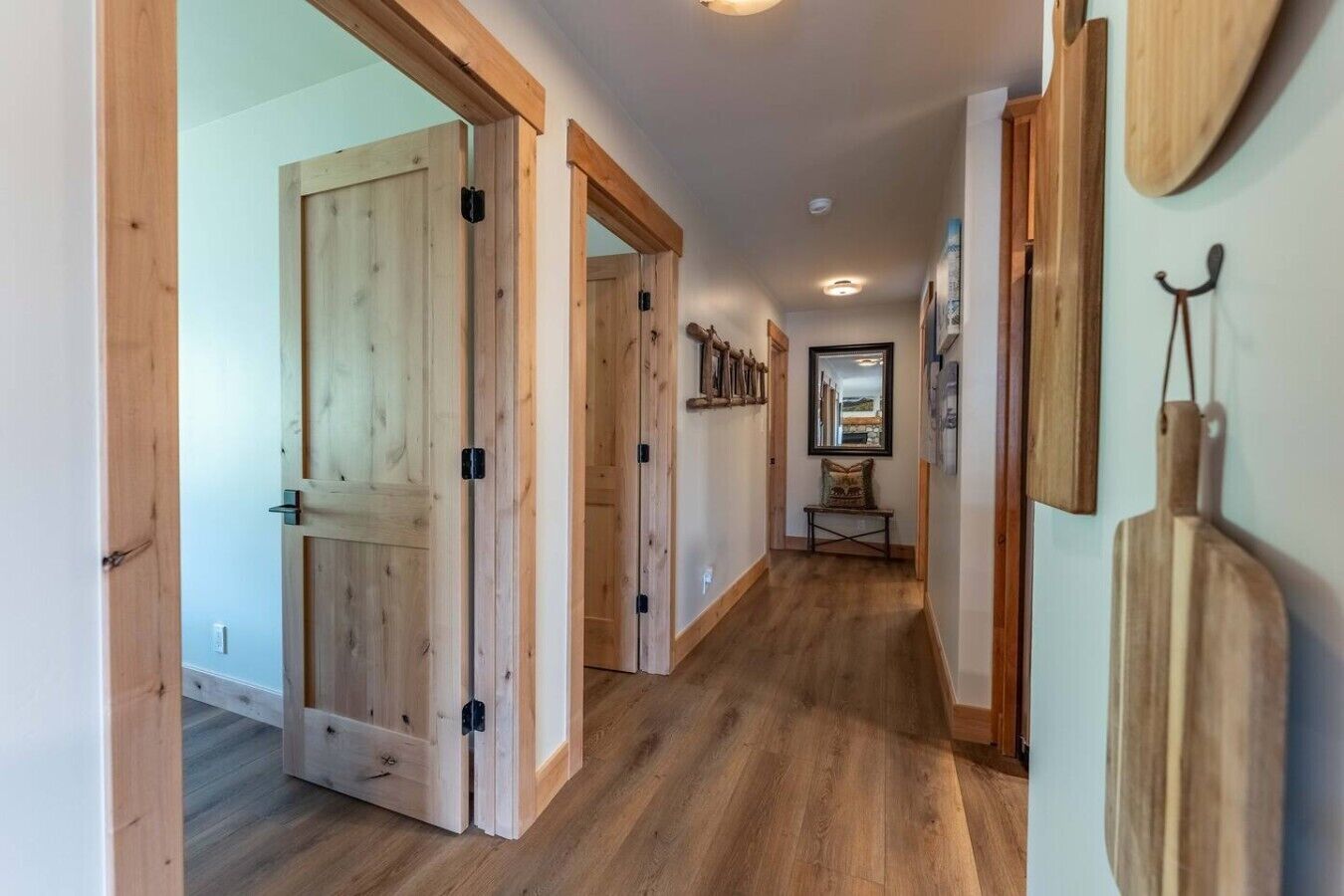 A hallway with wooden doors, a bench, and a mirror on the wall.